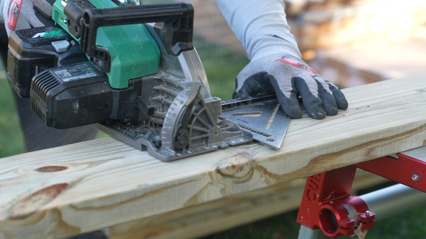 Deck builder cutting wood board with circular saw during construction in Tulare